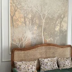 A serene, misty forest mural creates a peaceful backdrop behind a rattan sofa, perfectly complementing the natural textures in the room.