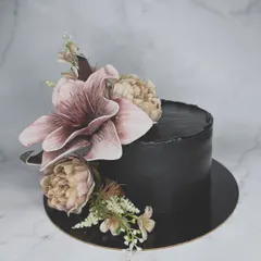 Is it a bouquet or a cake? This stunning black buttercream cake is adorned with large, handcrafted sugar flowers, creating a dramatic and artistic look for a sophisticated celebration.
