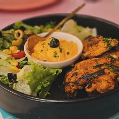 Eating out can be healthy too. This delicious plate of grilled chicken with a side salad and hummus is a perfect example. Being selective with your menu choices is the key to staying on track.