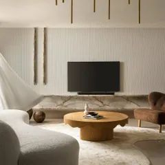 Another perspective of the Ecru Maison living room, highlighting the interplay of the curved sofa, the organic-shaped rug, and the solid oak coffee table. The design balances soft forms with the linear texture of the fluted wall and the drama of the marble console.
