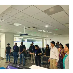 Participants standing and listening intently during a mindfulness meditation workshop at a corporate office.
