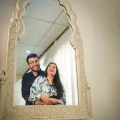 A moment of shared, uninhibited laughter captured in a mirror's reflection. This creative composition adds a unique and personal touch to your pre-wedding story.