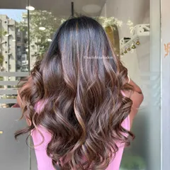 A full view from the back showing the length and volume of the hair after our highlighting service. The mix of light brown and caramel tones is distributed evenly for a natural, sun-lit appearance.