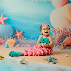 A magical mermaid photoshoot is a wonderful way to celebrate a first birthday. This shot captures a moment of pure delight, showcasing the detailed underwater set and adorable costume I provide.