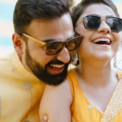Cool shades and warm smiles. This candid shot captures the fun, relaxed side of a Haldi ceremony, showing a couple sharing a moment of pure laughter together.