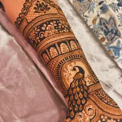 This forearm design showcases a beautiful peacock perched within an architectural arch (jharokha), a hallmark of traditional Rajasthani mehndi art.