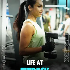 Life at FitDeck is about finding your strength and your smile. A female member holds a dumbbell, looking confident and happy in her fitness journey.
