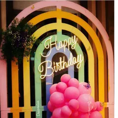 A vibrant and cheerful birthday setup with a rainbow-coloured arched backdrop. The "Happy Birthday" neon sign adds a modern glow, while the cluster of pink balloons at the base completes this fun and picture-perfect photo booth.
