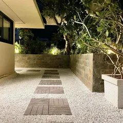 The same corporate terrace viewed at night. Thoughtful landscape lighting highlights the textures of the plants and the stone wall, transforming the space into an elegant retreat after dark. This shows the importance of a good lighting plan.