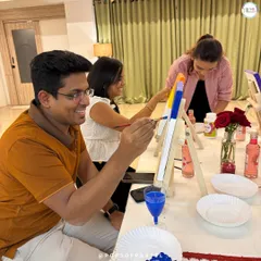 A candid shot from our Valentine's Day Sip and Paint event. Friends and couples laughing and painting together, with our instructor offering tips.