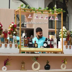 A close-up of the bartender's station at the Banaras-themed event. The decor details, including the hanging glasses and small floral arrangements, are consistent with the overall theme.