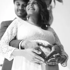 A beautiful, intimate black and white moment. The couple's hands forming a heart on the baby bump is a classic symbol of their shared love and excitement.