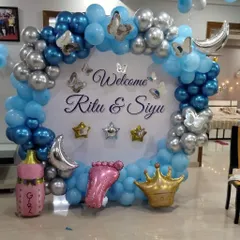 A beautiful welcome for baby Siyu and mom Ritu. This circular backdrop is framed with a blue and silver balloon arch and personalized with their names, along with cute foil balloons like a crown, moon, and baby foot.
