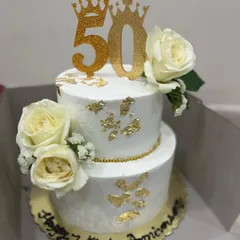 Celebrating a 50th work anniversary in style. This two-tiered Mango & Coconut Summer Cake is decorated with fresh white roses and edible gold leaf for a classic white and gold theme.