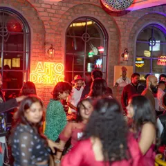 A wider view of the party, with me at the decks under the 'Afrodisiac' neon sign. The venue was filled with people enjoying the music and the vibrant, brick-and-neon aesthetic.