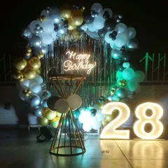 A stylish rooftop decoration for a 28th birthday, with a balloon ring, shimmer curtain, and light-up numbers creating the perfect party spot.