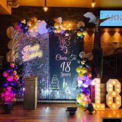 Another view of the stylish 18th birthday decor. The balloon arch in purple, black, and gold adds a festive touch to the glamorous sequin wall and custom signage.