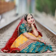 A quiet, thoughtful pose on the railway tracks. This composition focuses on the model's expression and the beautiful drape of the multi-colored lehenga, telling a story with the scene.