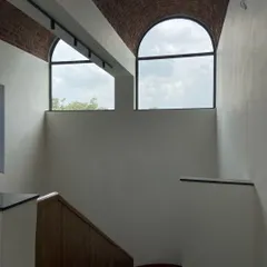 The large arched windows at the end of the brick vault, designed to let in natural light and offer views of the sky and surrounding flora.