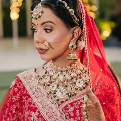 A close-up of this classic red bridal look. I focused on creating flawless, glowing skin and defining the eyes to complement her beautiful green and kundan jewellery. This is timeless elegance.