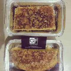 This is Handvo, a traditional savory cake made from rice, lentils, and vegetables like bottle gourd. It's baked until golden and is a wholesome, nutritious snack, delivered in convenient foil containers.