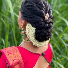 A side view of the intricate braided bun, adorned with fresh jasmine flowers. This is a popular choice for guests at South Indian functions.