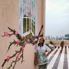 Guess I said yes to heaven. Me looking up at a finished terrace mural that features a whimsical window opening to a world of blossoms, with flowering branches wrapping around it.