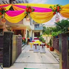 A closer view of the entrance area for a Mehandi and Sangeet function. The draped canopy is accented with floral bouquets and dreamcatchers, and chairs are set up for guest seating.