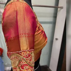 A side view of the red and orange bridal blouse, showing the traditional puff sleeve with a heavily embroidered zardosi cuff. This style adds a touch of regal elegance to any bridal saree.