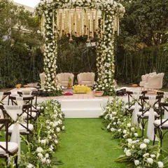 An elegant outdoor mandap, framed by pillars of white roses and lush greenery. We work with you to design a sacred space that feels both traditional and contemporary, ensuring the setting for your vows is as beautiful as the commitment you are making.