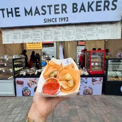 A customer holding a fresh serving of our crispy fried wontons at our outdoor stall. These golden pockets are filled with a savory vegetable mix and served with a tangy dipping sauce, perfect for a quick and satisfying snack.