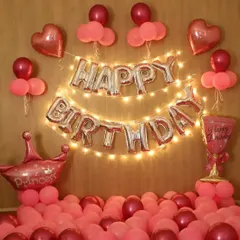 A sweet "Happy Birthday Princess" decoration. This pink-themed setup includes foil letters with fairy lights, heart and crown-shaped balloons, and lots of balloons on the floor.