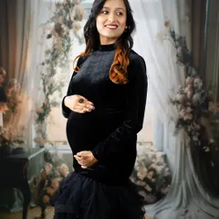 A touch of elegance in a casual style. This mom-to-be wears a black velvet dress with a tulle skirt, creating a look that is both comfortable and chic in our floral window setup.