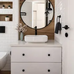 This contemporary bathroom features a beautiful mix of textures, with white subway tiles and a wood-panelled accent wall. The round mirror and floating vanity keep the design clean and elegant.