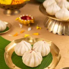 Classic steamed modaks, garnished with saffron. I styled this shot with a banana leaf and a brass plate for a simple, clean, and traditional look that focuses on the purity of the sweet.