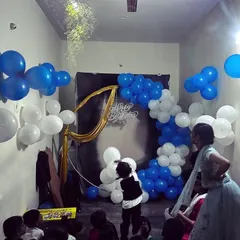 A classic blue and white balloon arch paired with a simple black backdrop and gold fabric drape. This shows how we can create an attractive and budget-friendly photo booth area for a kids' birthday party at home.