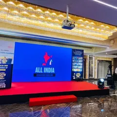 The stage for the All India Achievers Conclave. This setup features a clean, branded look with a central LED screen for presentations, a raised platform for visibility, and professional lighting to create a formal atmosphere.