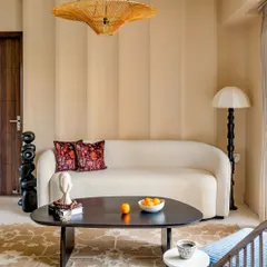 A full view of the 'Project Lily' living room, highlighting the blend of textures and earthy tones. The space is furnished with a custom sofa, a unique totem-pole-style floor lamp, and a patterned rug.