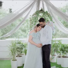 A heartwarming couple's maternity photo. The light blue gown complements the partner's attire perfectly, creating a cohesive and loving portrait.