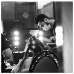 An atmospheric shot of our hairstylist at work in front of our portable, lighted vanity. This setup allows us to deliver studio-quality results no matter the location.