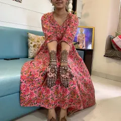 A happy client showing her complete mehndi set, including designs on her hands and feet. The foot design is a simple yet elegant mandala that matches her hand patterns.