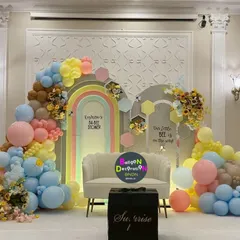 A vibrant and colorful baby shower combining a rainbow arch with a "little bee is on the way" theme, showing how we can merge ideas.