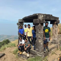 A group resting at the ancient stone Mantapa on the way to Kumara Parvatha peak. These structures provide a glimpse into the history of this trail.