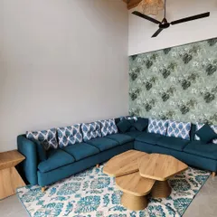 This angle shows the interplay of patterns and textures in the villa's living room. The floral wallpaper adds a touch of nature indoors, complementing the organic shape of the custom coffee table and the patterned rug.