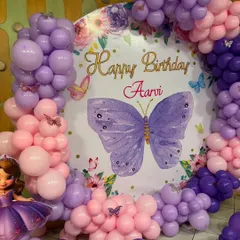 A beautiful butterfly theme for Aarvi's birthday. This circular backdrop is surrounded by a pink and purple balloon arch, creating a perfect photo spot.