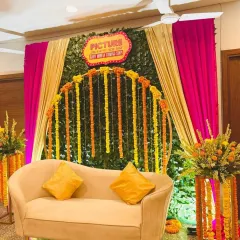 For a traditional Godh Bharai with a twist, we designed this vibrant 'Filmy' theme. The combination of a lush green wall, bright marigold garlands, and dramatic draping creates a festive and uniquely Indian celebration space.