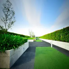 This intensive garden is built for accessibility and structure. The design includes paved walkways, raised concrete planters for lush hedges, and green turf, creating a clean, contemporary, and usable rooftop park.
