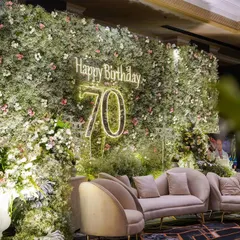 The main photo-op for the 70th birthday party. I created a lush wall of greenery and white flowers with a custom neon sign, providing a beautiful and personal backdrop for photos.