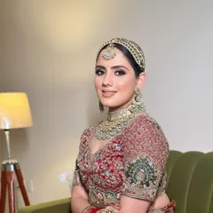 A royal bridal look featuring a sleek, center-parted bun that perfectly accommodates the traditional matha patti jewelry. This clean hairstyle ensures the focus remains on the bride's stunning features and ornate accessories.
