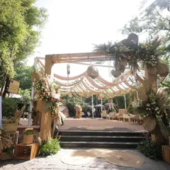 This entrance was designed for a bohemian-chic daytime event. We used natural materials like jute fabric for the drapes and large arrangements of pampas grass and dried palms to create an earthy and organic feel.